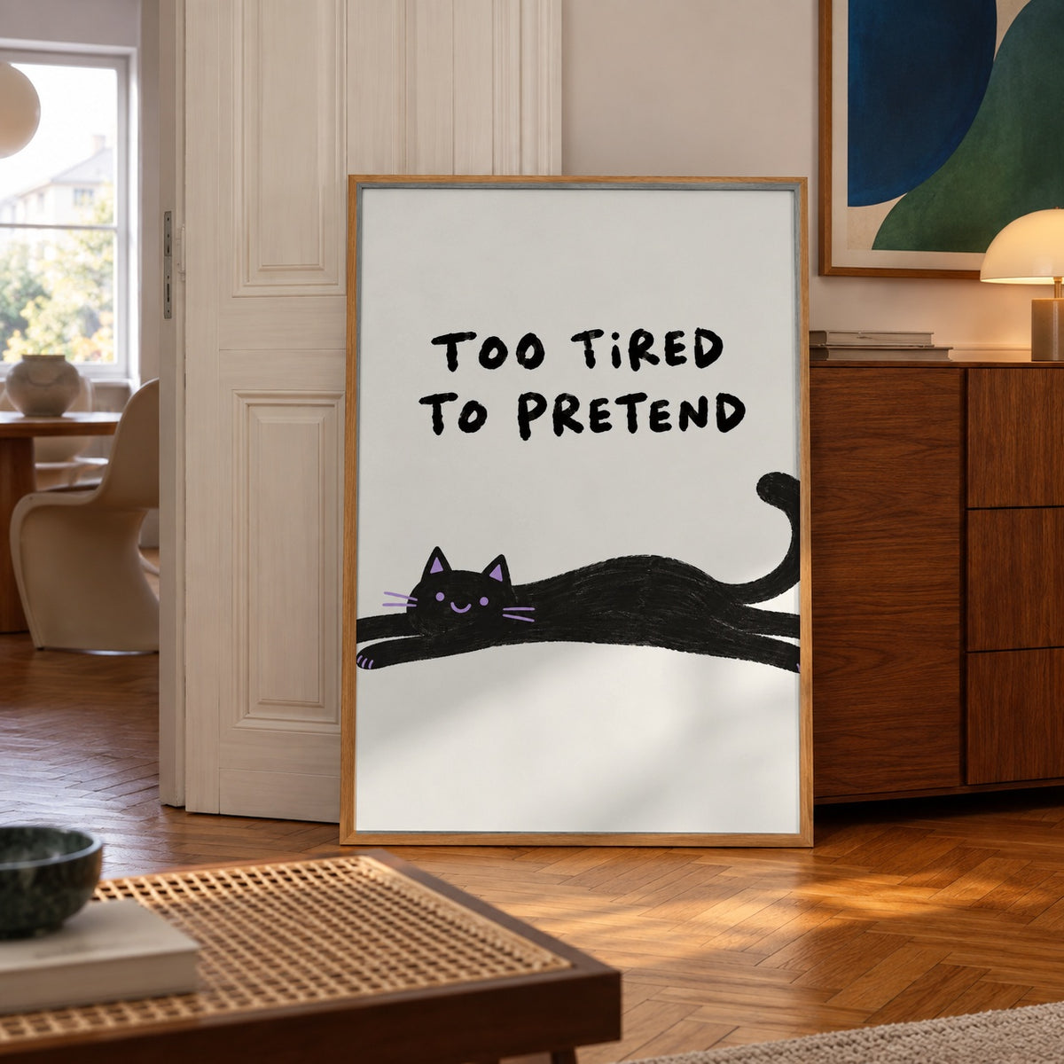 A sprawled-out black cat with a cheeky little smile, too tired to pretend anymore — poster displayed in a styled room